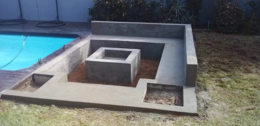 Sunken seating area with square fire pit beside a pool
