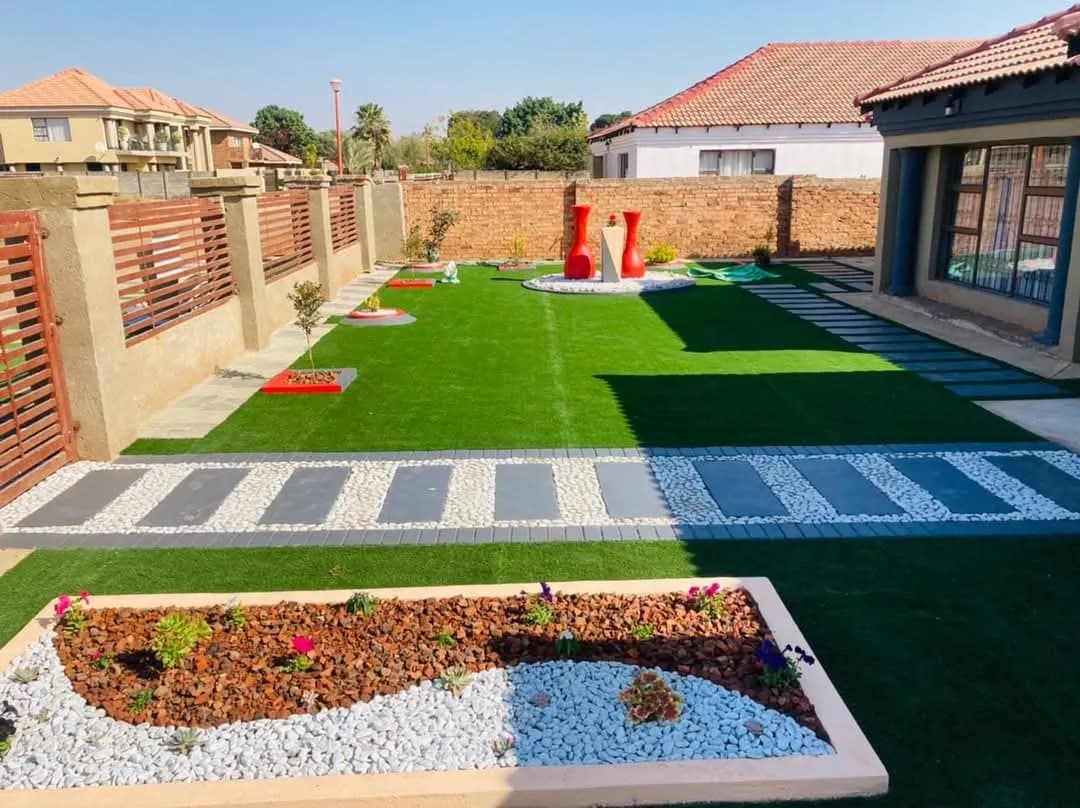 Back garden with artificial lawn, paver walkway and pebble-filled planter