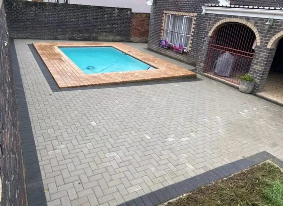 Paved courtyard around a swimming pool with charcoal border