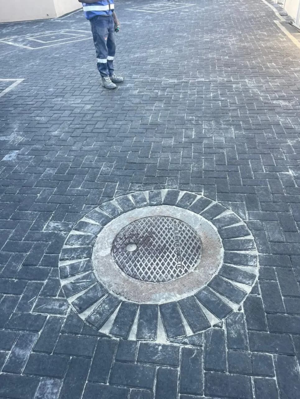 Charcoal paving with circular brick detail around a manhole