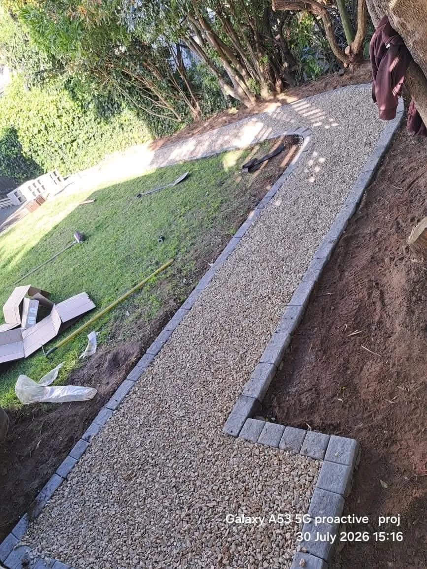 Gravel path being installed beside a lawn with brick edging