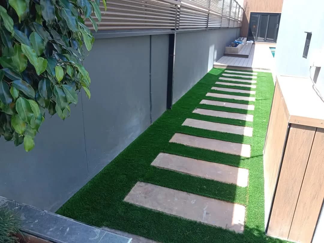 Narrow side garden with stepping pavers in artificial grass